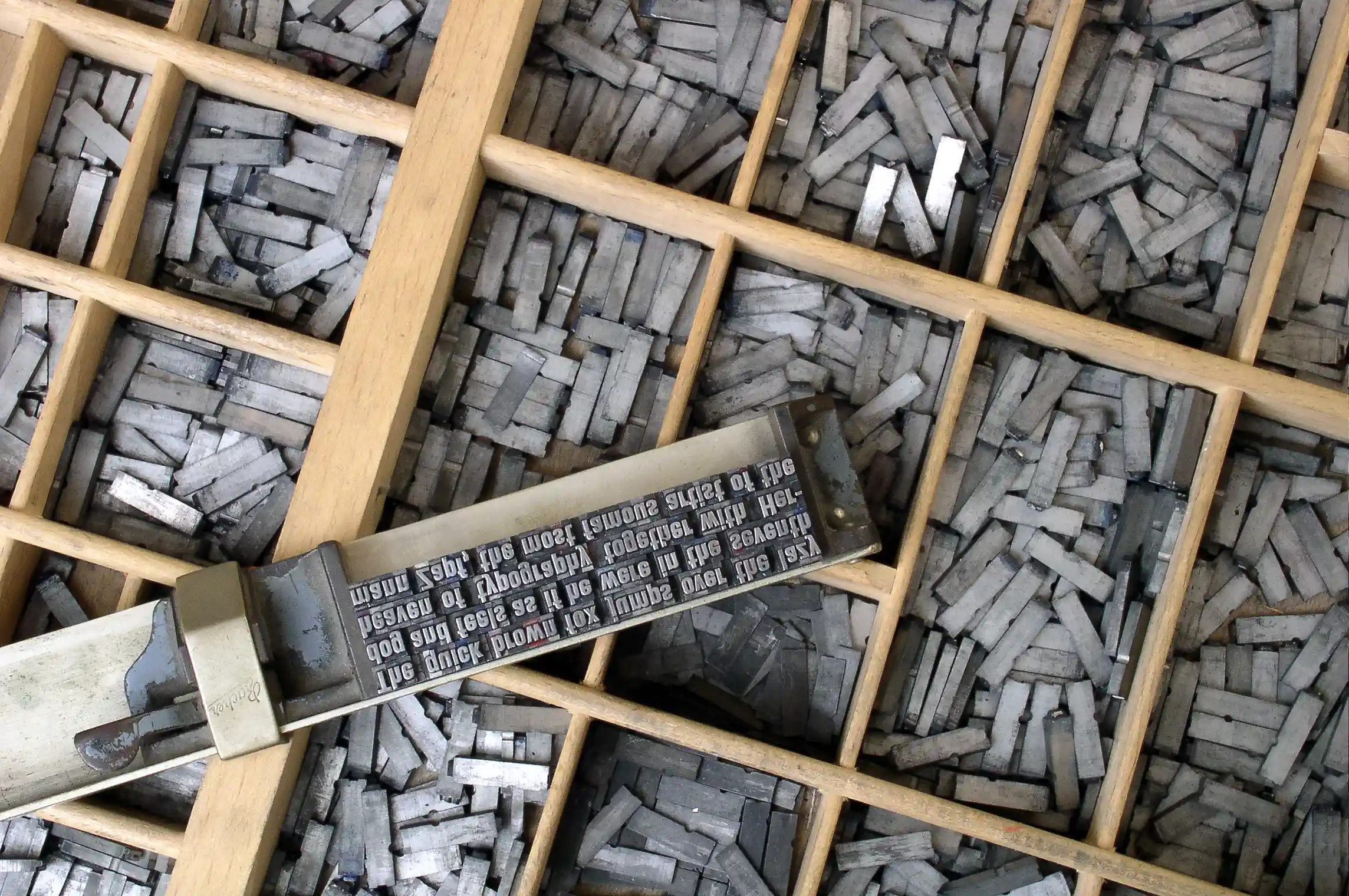 Figure 2: Metal types in letter cases and a composing stick. (By Willi Heidelbach. Wikipedia, CC BY 2.5.)