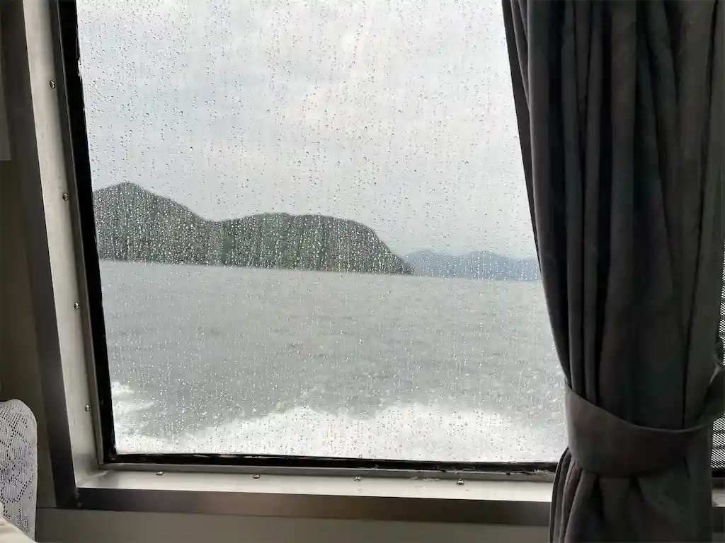 雨がついた窓から海が見える