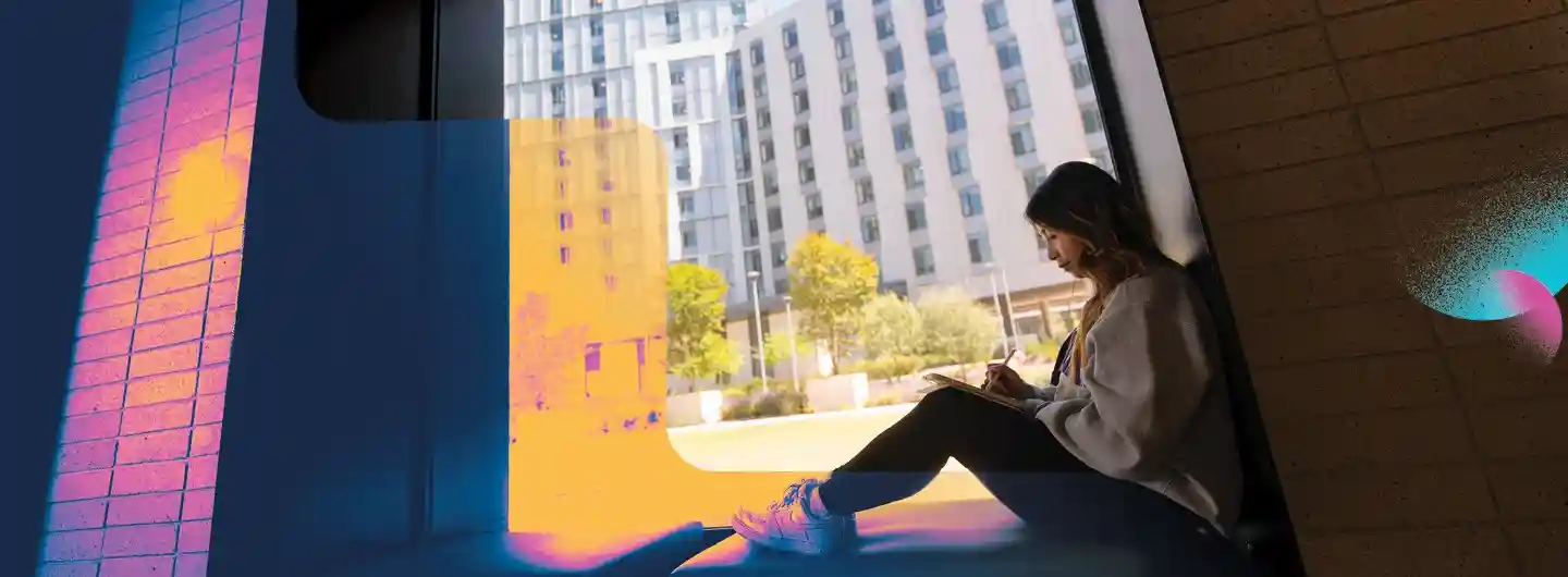 Student working on computer outside of dorms
