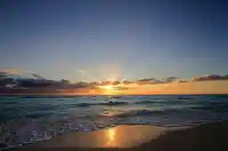 a regal sun rising upon the beach