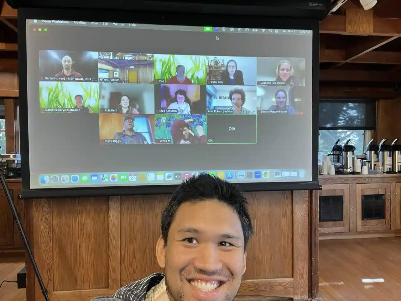 A person taking a selfie with a Zoom screen filled with images of people.