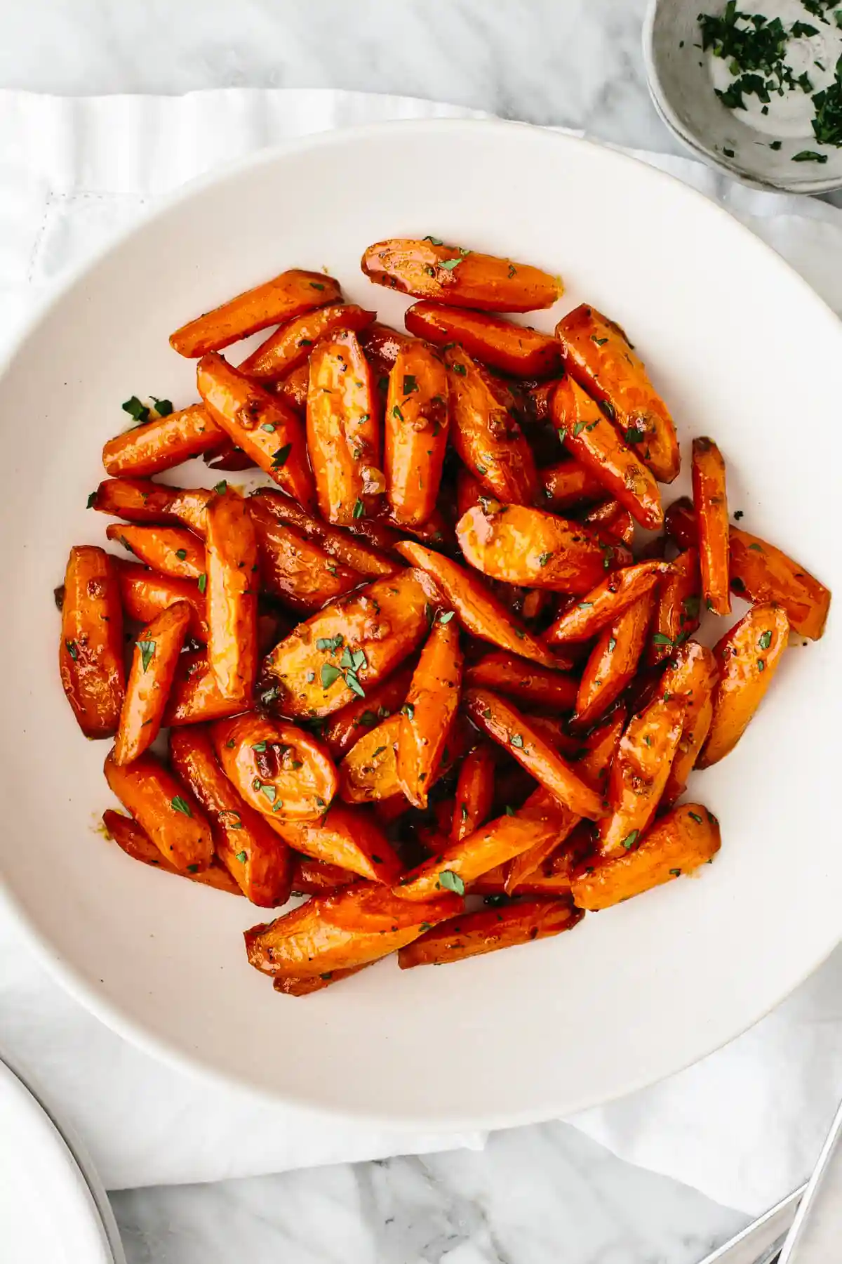 Honey glazed carrots in a white bowl on a table.