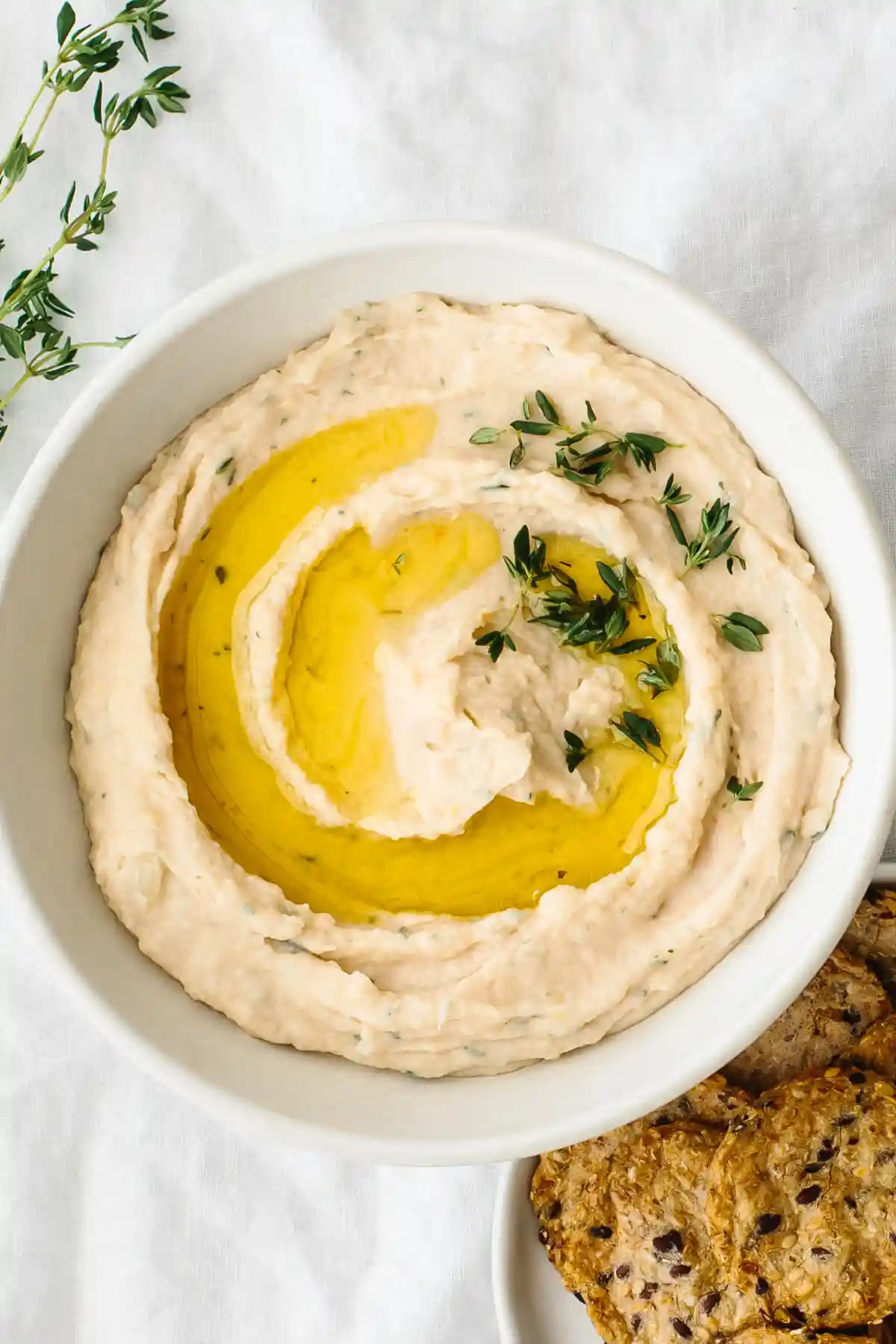 White bean dip in a bowl next to crackers.