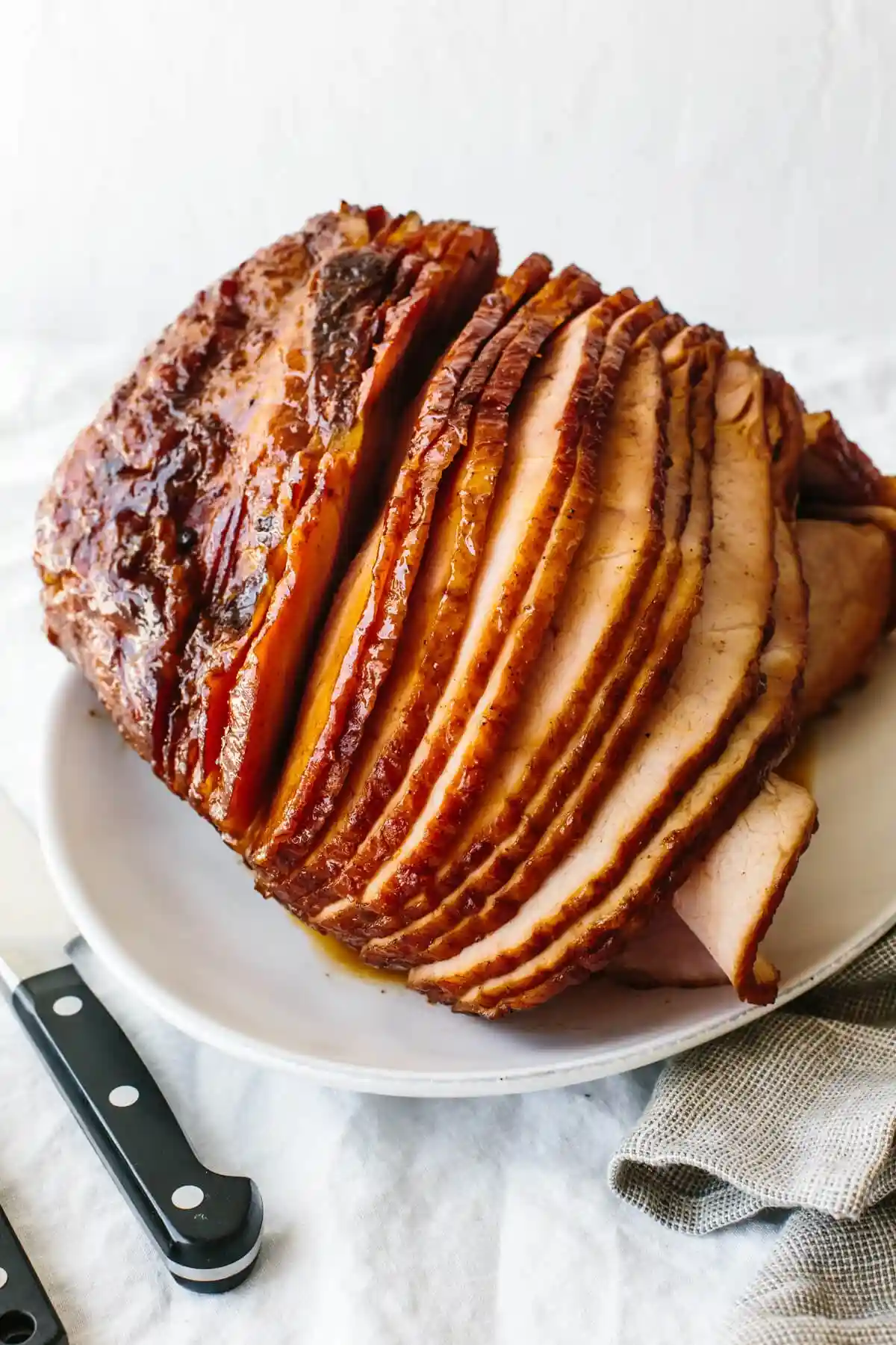 Honey baked ham on a plate next to a knife