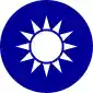 A blue circular emblem on which sits a white sun composed of a circle surrounded by 12 rays.