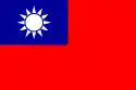A red flag, with a small blue rectangle in the top left hand corner on which sits a white sun composed of a circle surrounded by 12 rays.