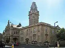 Stone building with colonnaded entrance. Above is a clock tower.