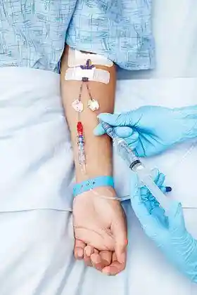 Photo of a person being administered fluid through an intravenous line or cannula in the arm.