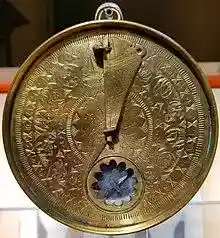 Circular brass time measurement device with engraved Arabic toponyms and zodiac symbols.