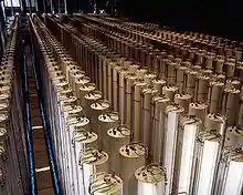 A photo of a large hall filled with arrays of long white standing cylinders.