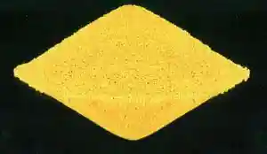 A yellow sand-like rhombic mass on black background.