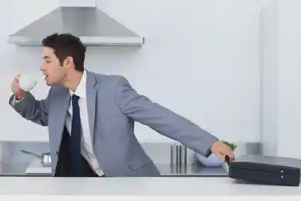 A late businessman taking his briefcase and drinking a coffee while going to work
