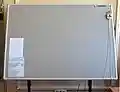 A large-format graphic tablet by manufacturer Summagraphics (OEM'd to Gerber): The puck's external copper coil can be clearly seen. Note using of a Digitizer mouse with a magnifying glass.
