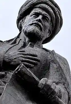 A color photograph of a black statue of a bearded and turbaned man