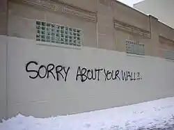 graffiti art on a wall stating "SORRY ABOUT YOUR WALL"