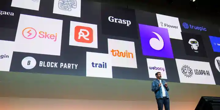 Relatore sul palco con loghi di vari prodotti.